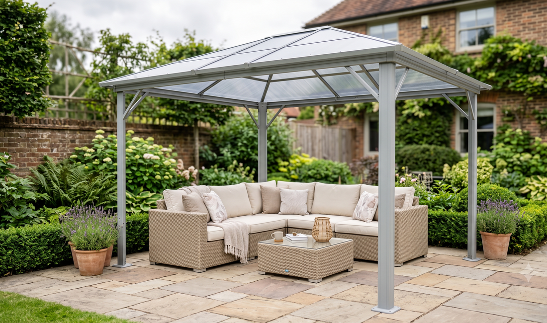 Modern grey hardtop gazebo with polycarbonate roof and beige rattan corner sofa in a compact UK suburban garden with potted l