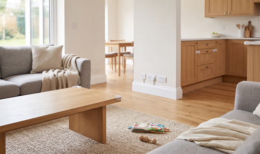 Bright, airy UK semi-detached living room with toddler-safe socket covers, cupboard locks, and a soft corner guard on wooden 