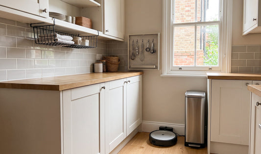 Bright, tidy UK terraced house kitchen with wall-mounted shelves, under-cabinet baskets, and a compact ECOVACS robot vacuum i